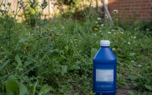Un jardin avec des mauvaises herbes et un flacon d'AdBlue, illustrant les risques de son utilisation.