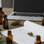 Analyse de laboratoire CBD sur une table avec flacons et feuilles de cannabis.